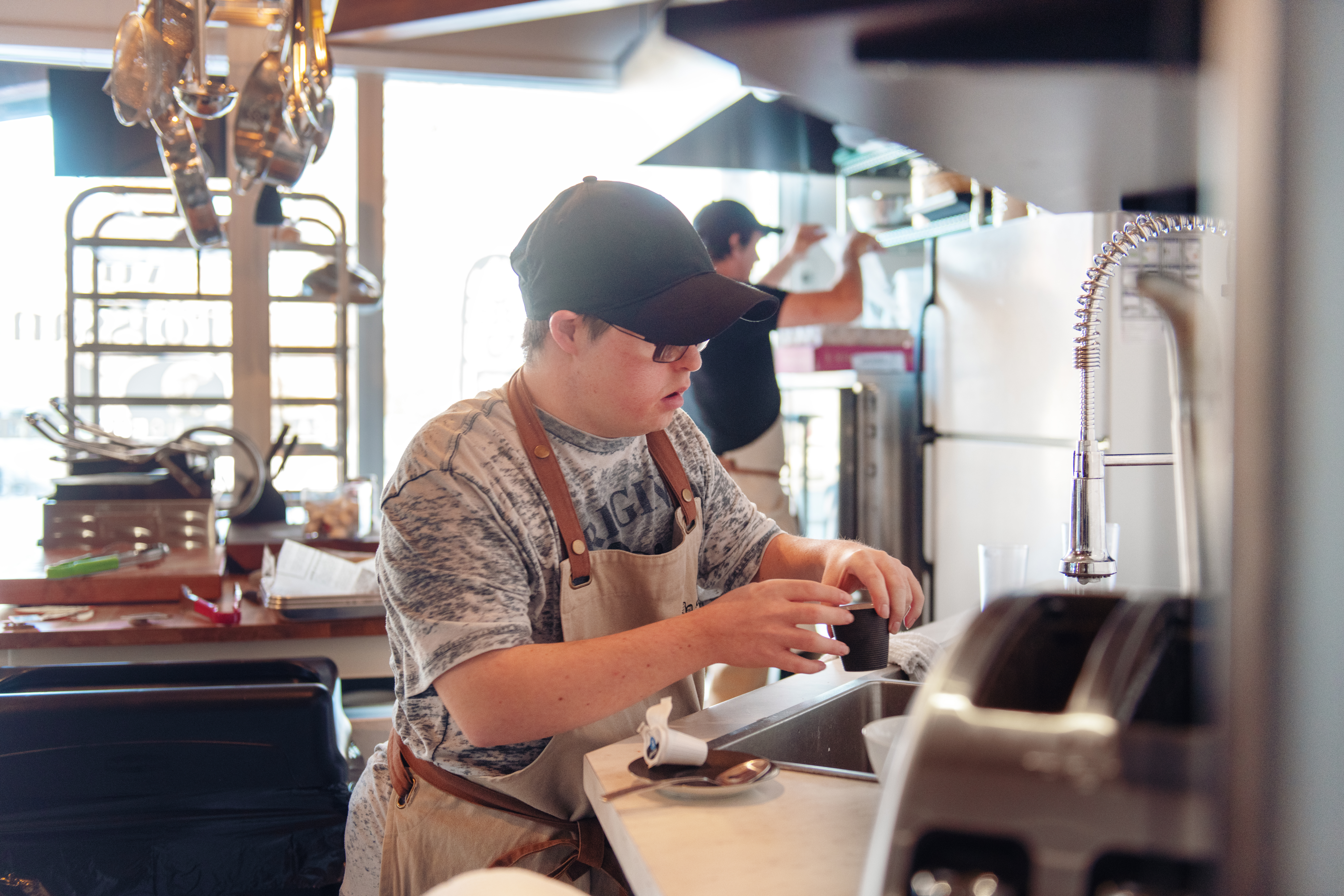 A man cleans dishes inside the kitchen of a small business.