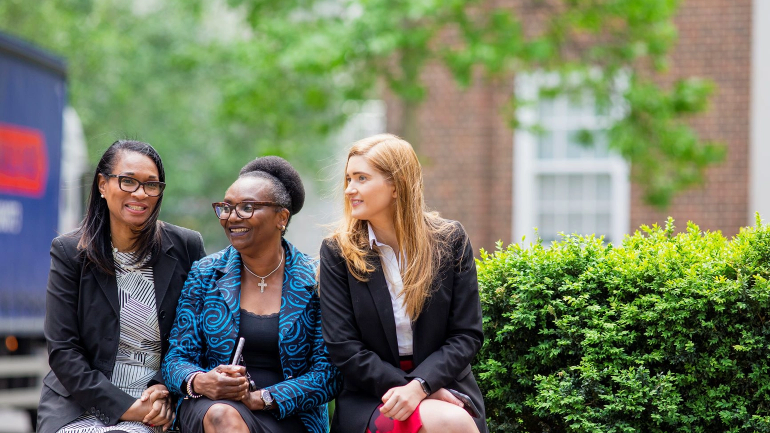 Three female coworkers sitting in the bench together Three female coworkers sitting in the bench together