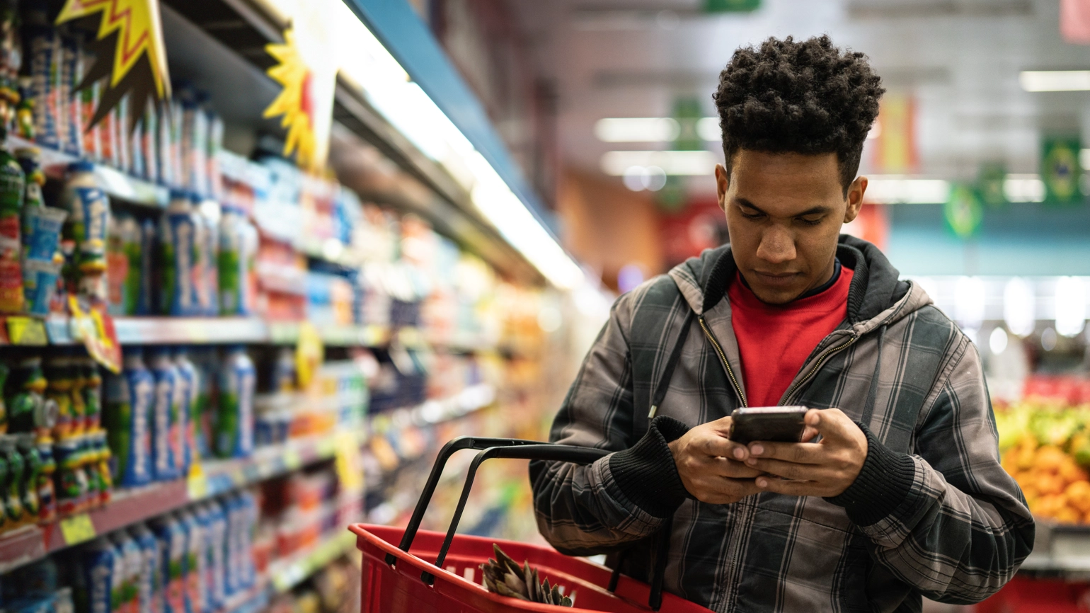 A man looks at his phone as he shops in a supermarket. A man looks at his phone as he shops in a supermarket.
