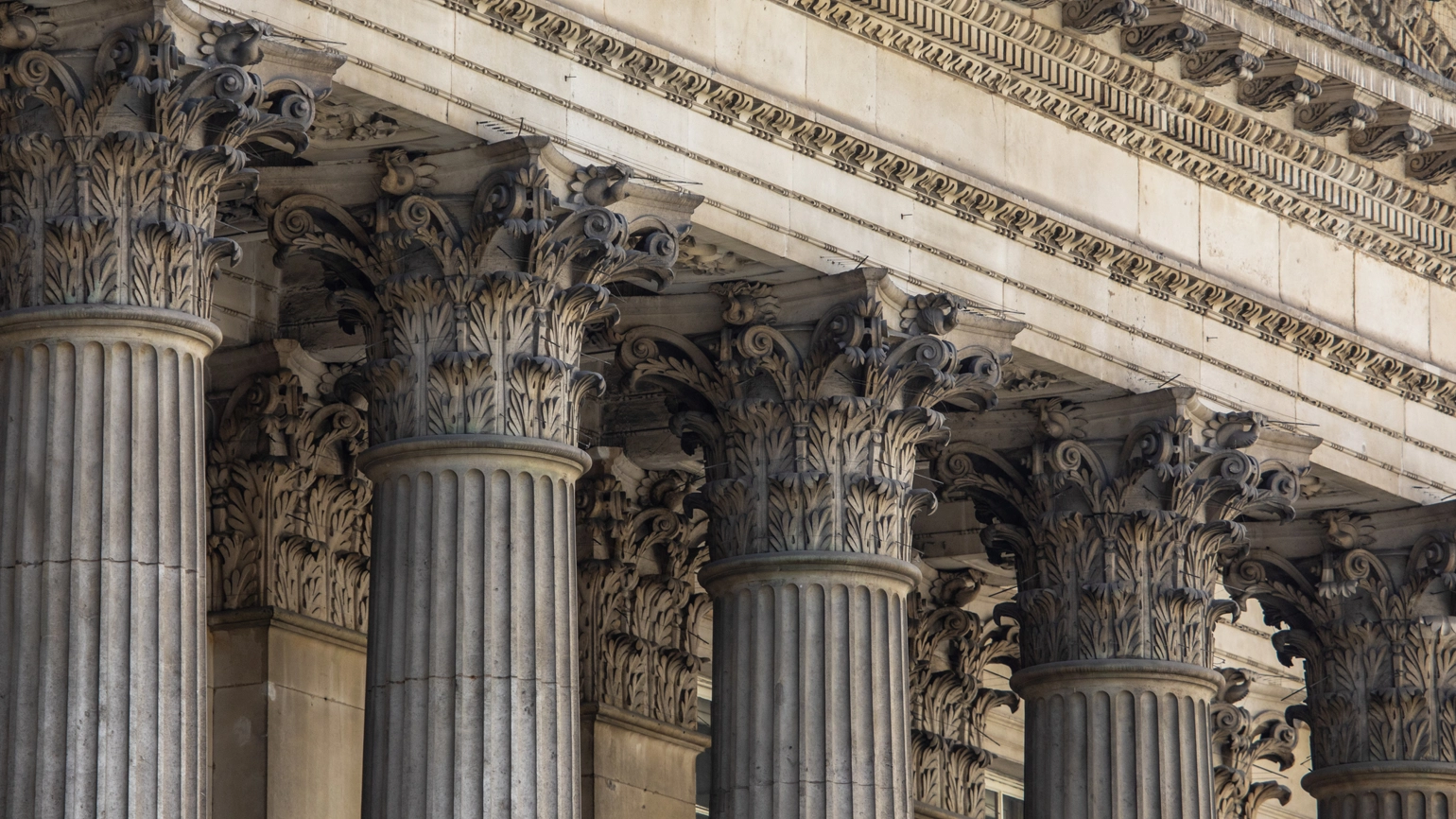 Close-up view of ornate Corinthian columns on a classical stone building façade. Close-up view of ornate Corinthian columns on a classical stone building façade.