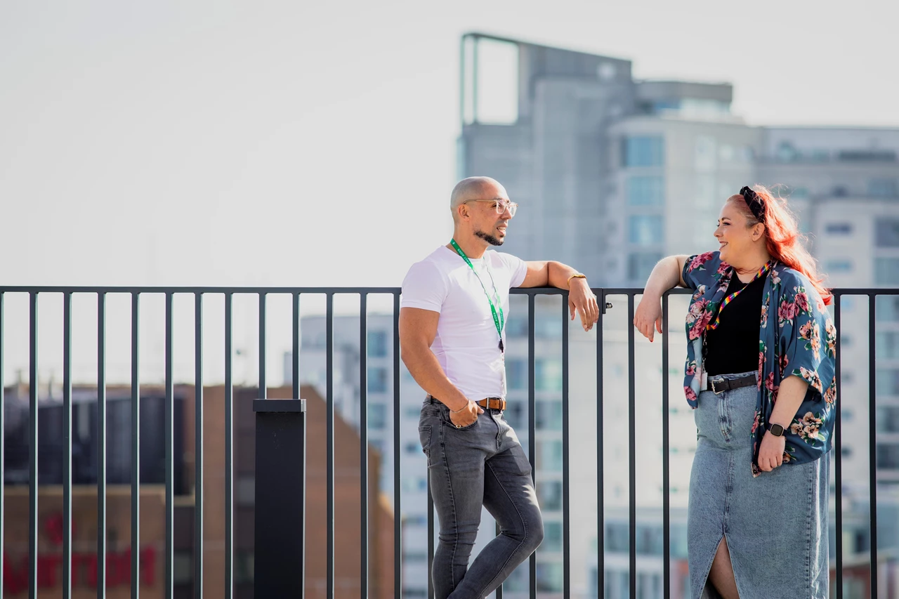 Photograph of a man and woman talking outside against backdrop of city