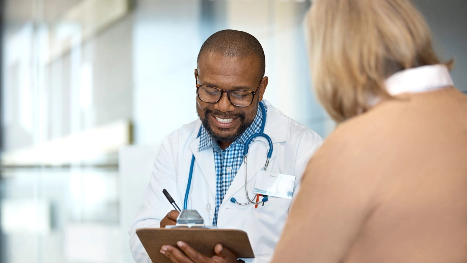 A smiling doctor reviews a medical record with female patient. A smiling doctor reviews a medical record with female patient.
